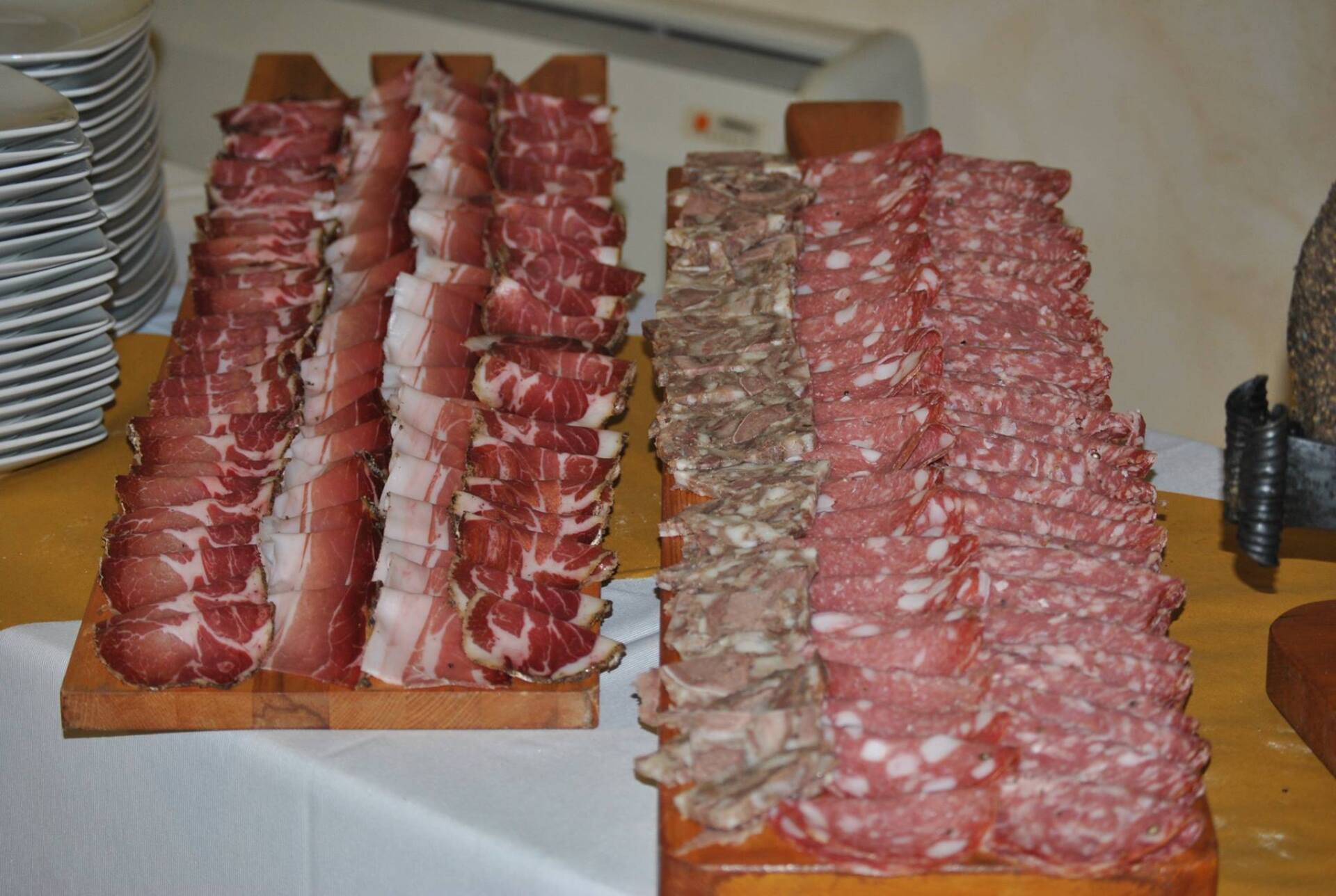 Salumi affettati esposti su taglieri di legno.