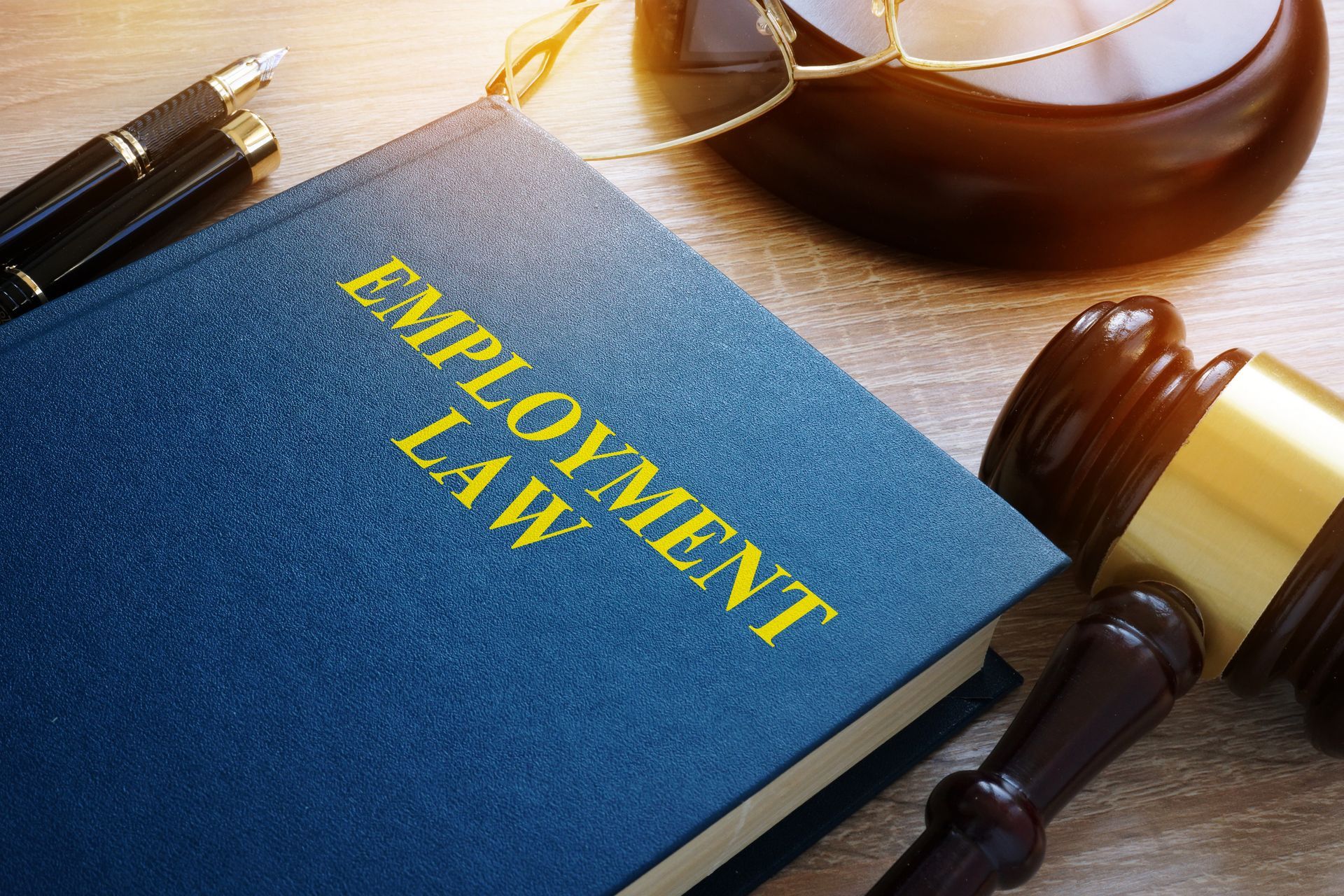 Employment law book with a gavel and glasses on a wooden desk.
