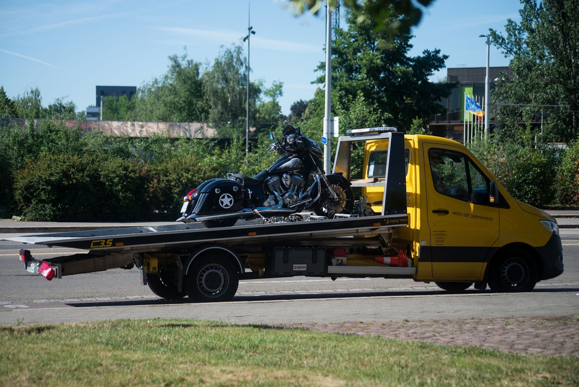 A damaged car loaded on a car hauler on a highway; sunny day.