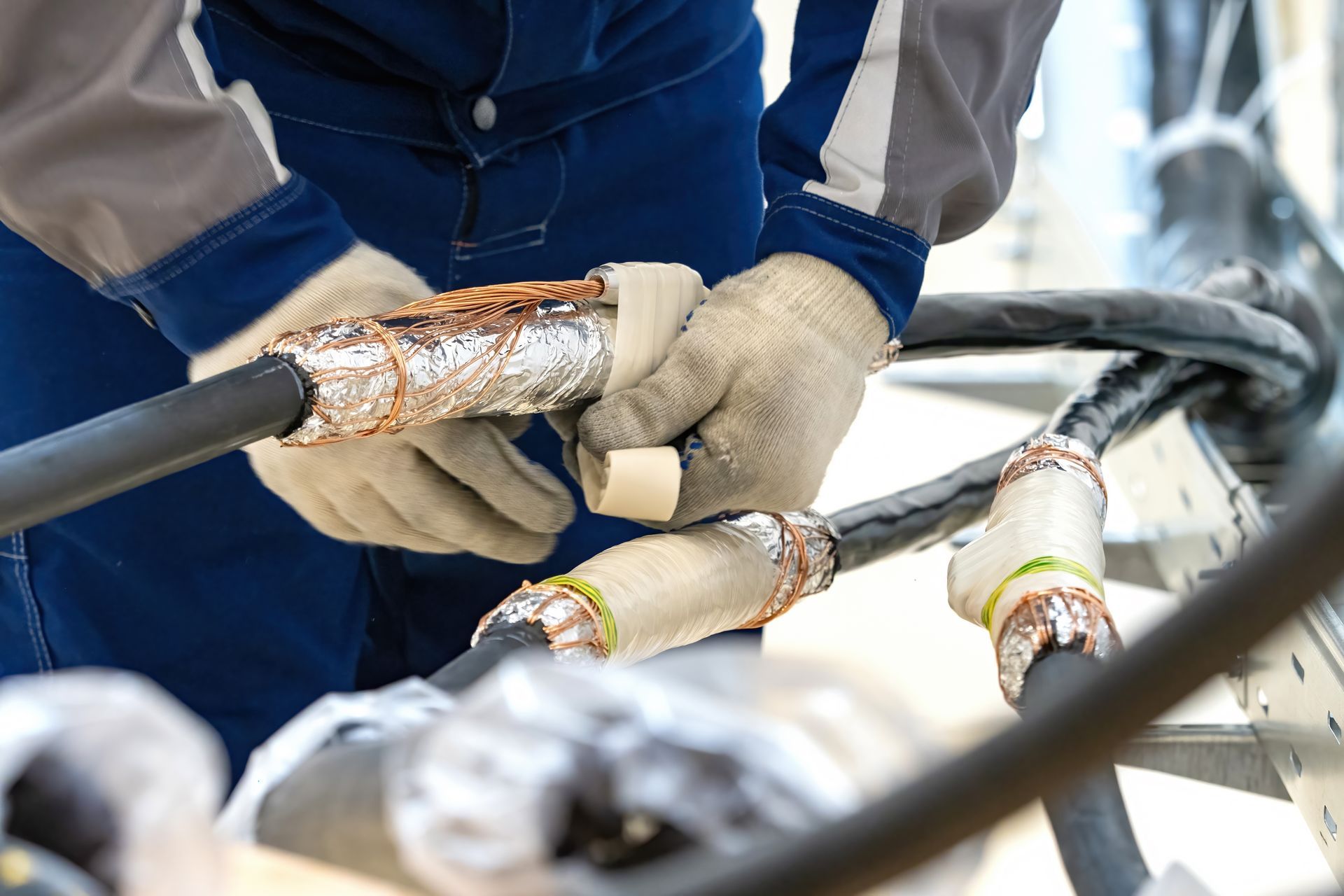 Worker splicing insulated cables with protective gloves at a job site