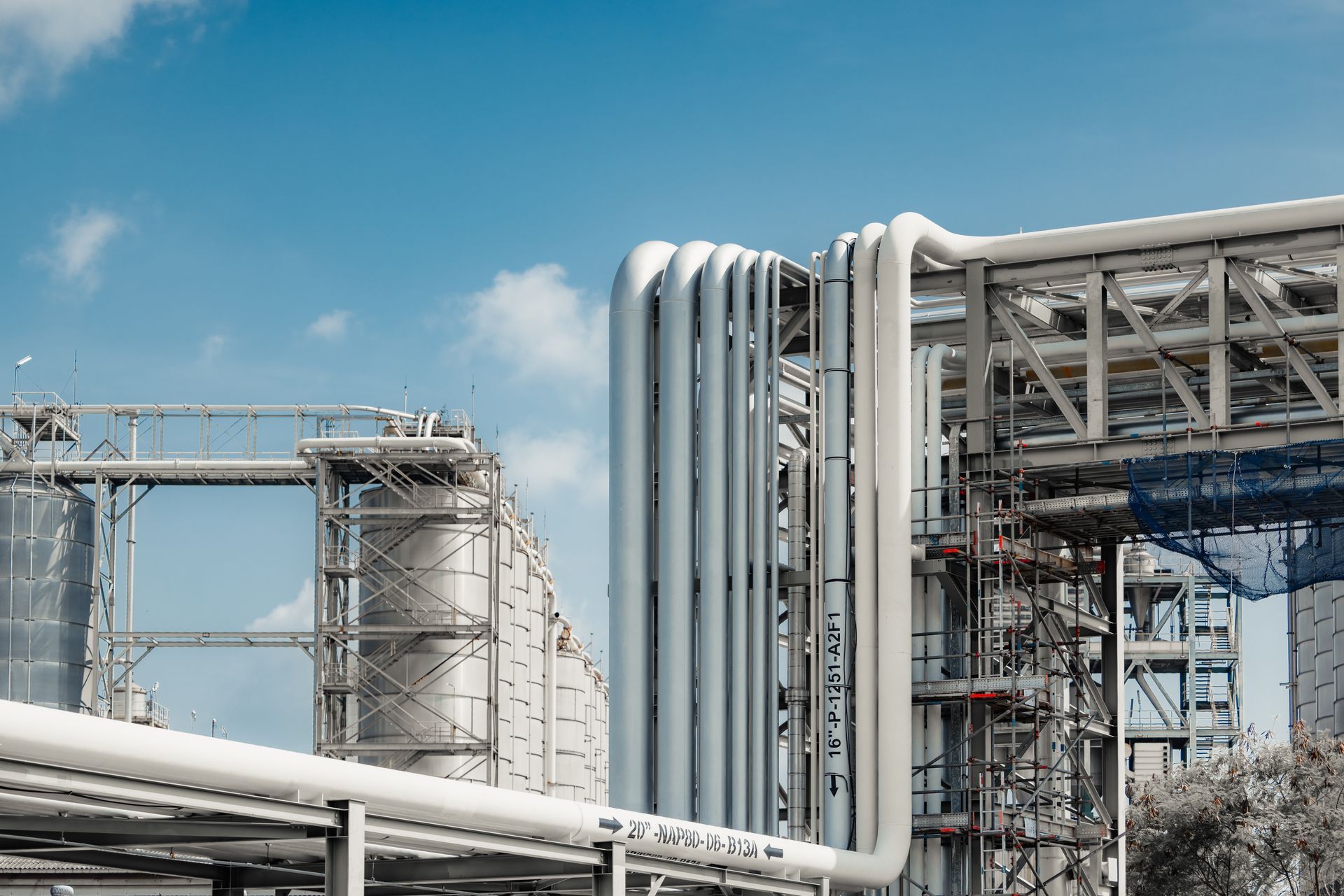 Industrial plant with silver pipes and metal structures under a blue sky