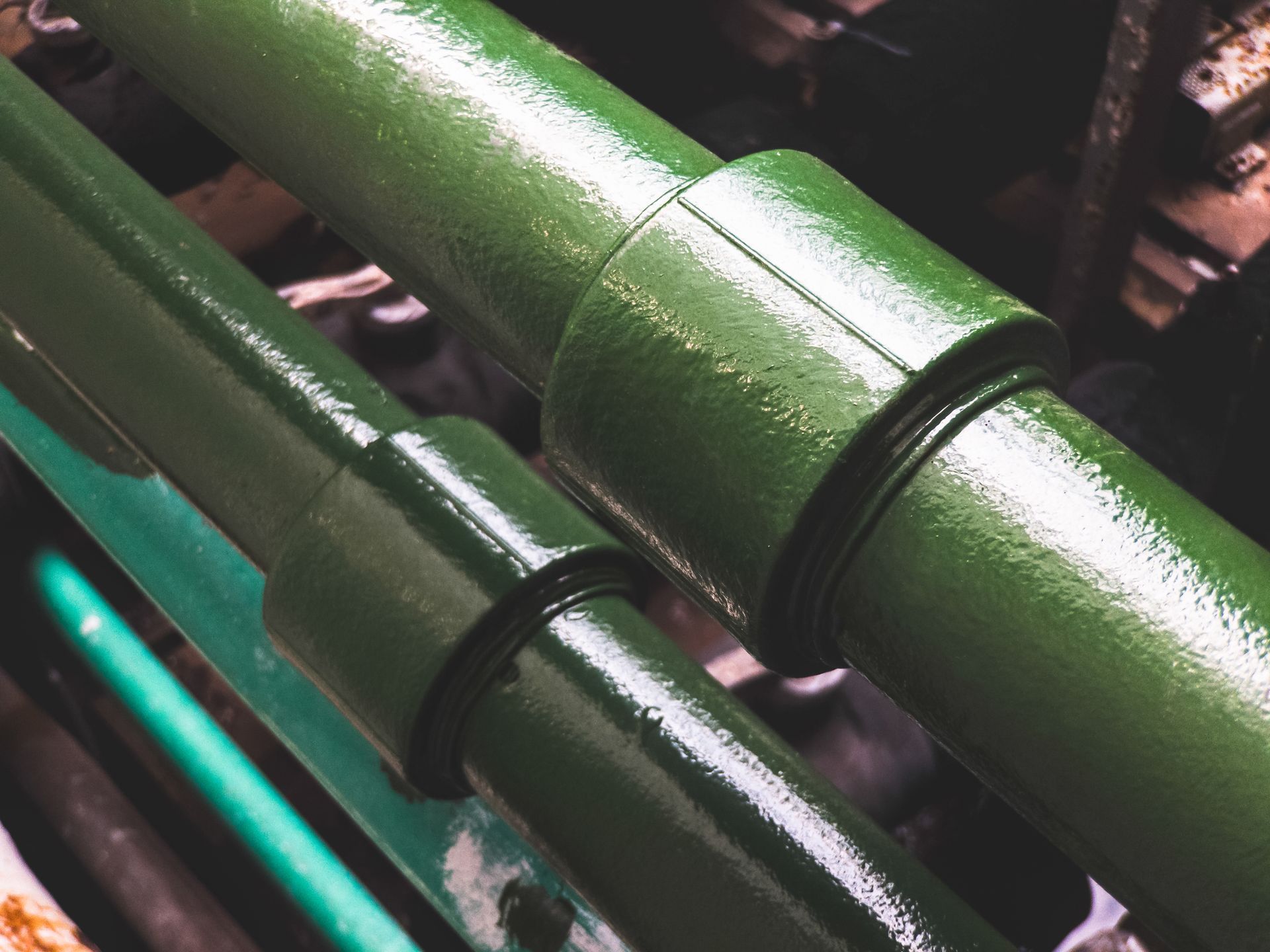 Green metal pipes with glossy coating running diagonally in an industrial setting