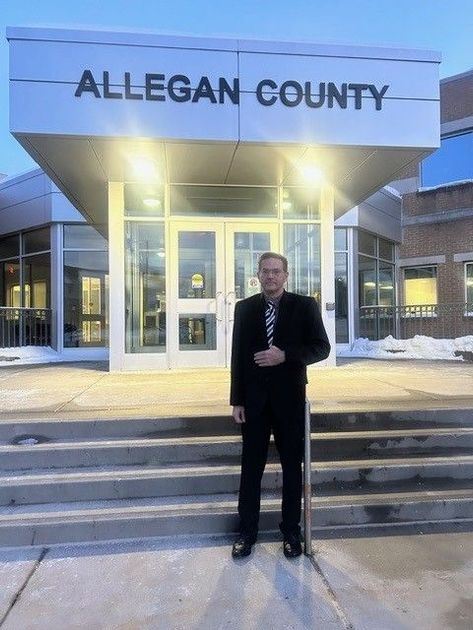 Man in suit standing in front of Allegan County building.