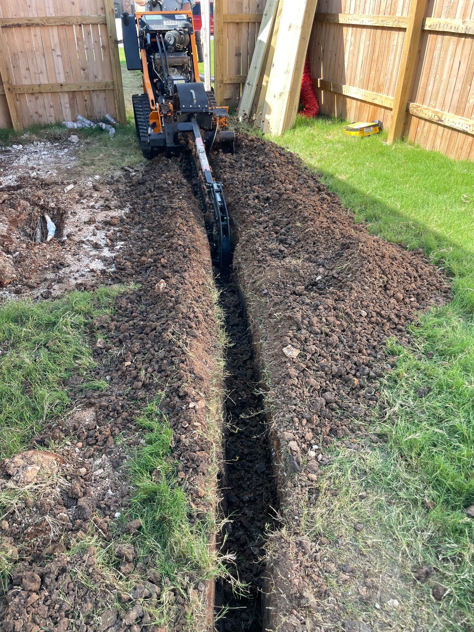 A machine is digging a hole in the ground in a yard.