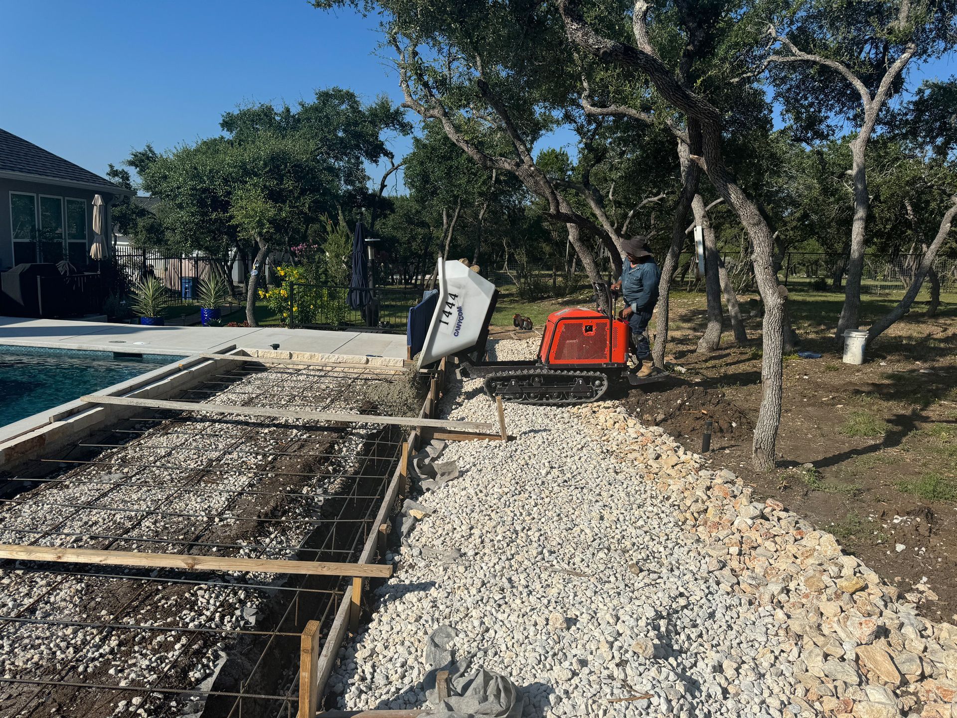 A tractor is being used to pour concrete in a yard.
