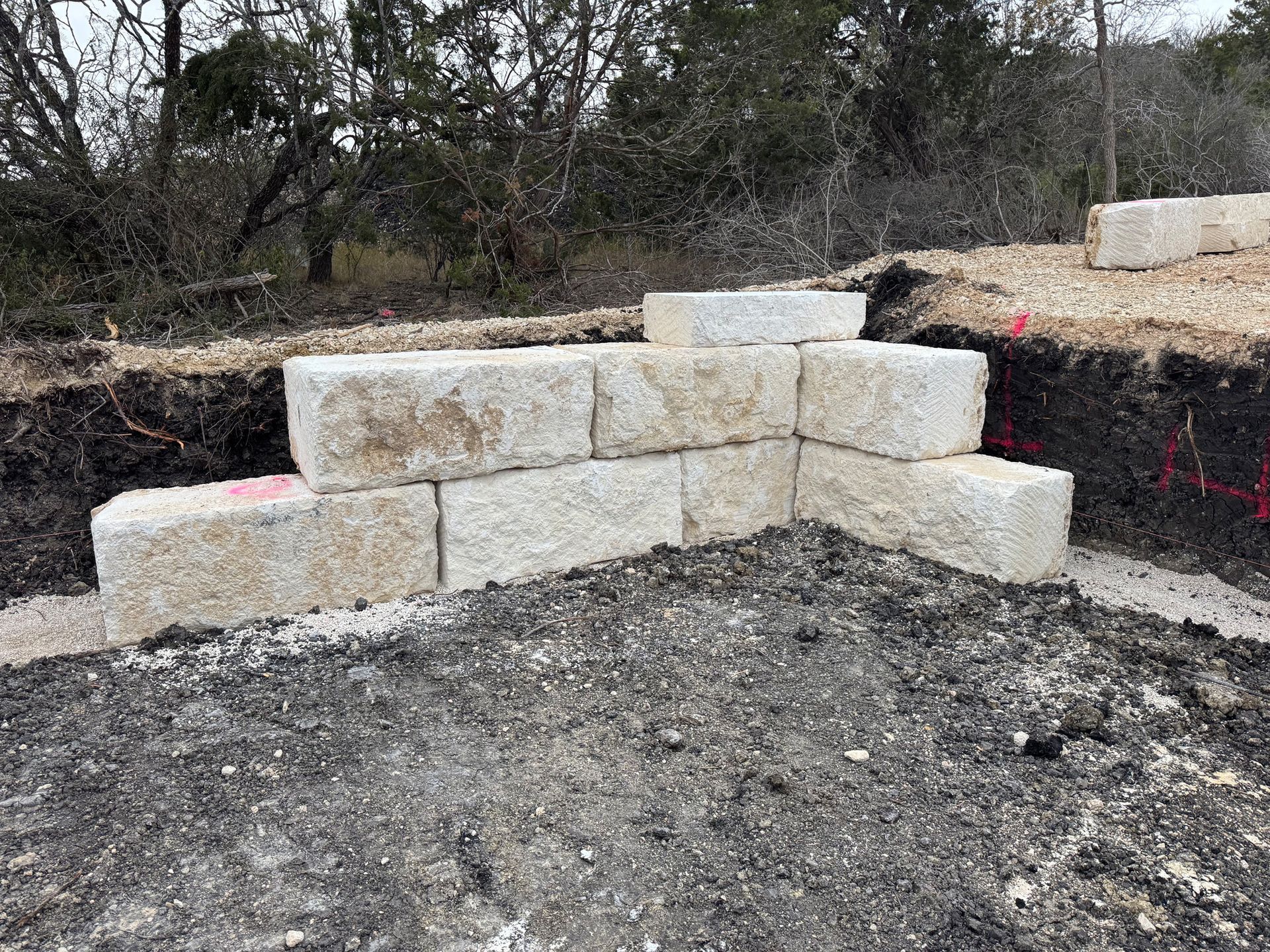 A stone wall is being built on top of a dirt field.