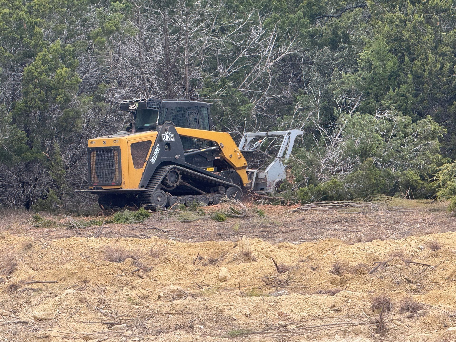 A bulldozer is cutting down trees in a field.