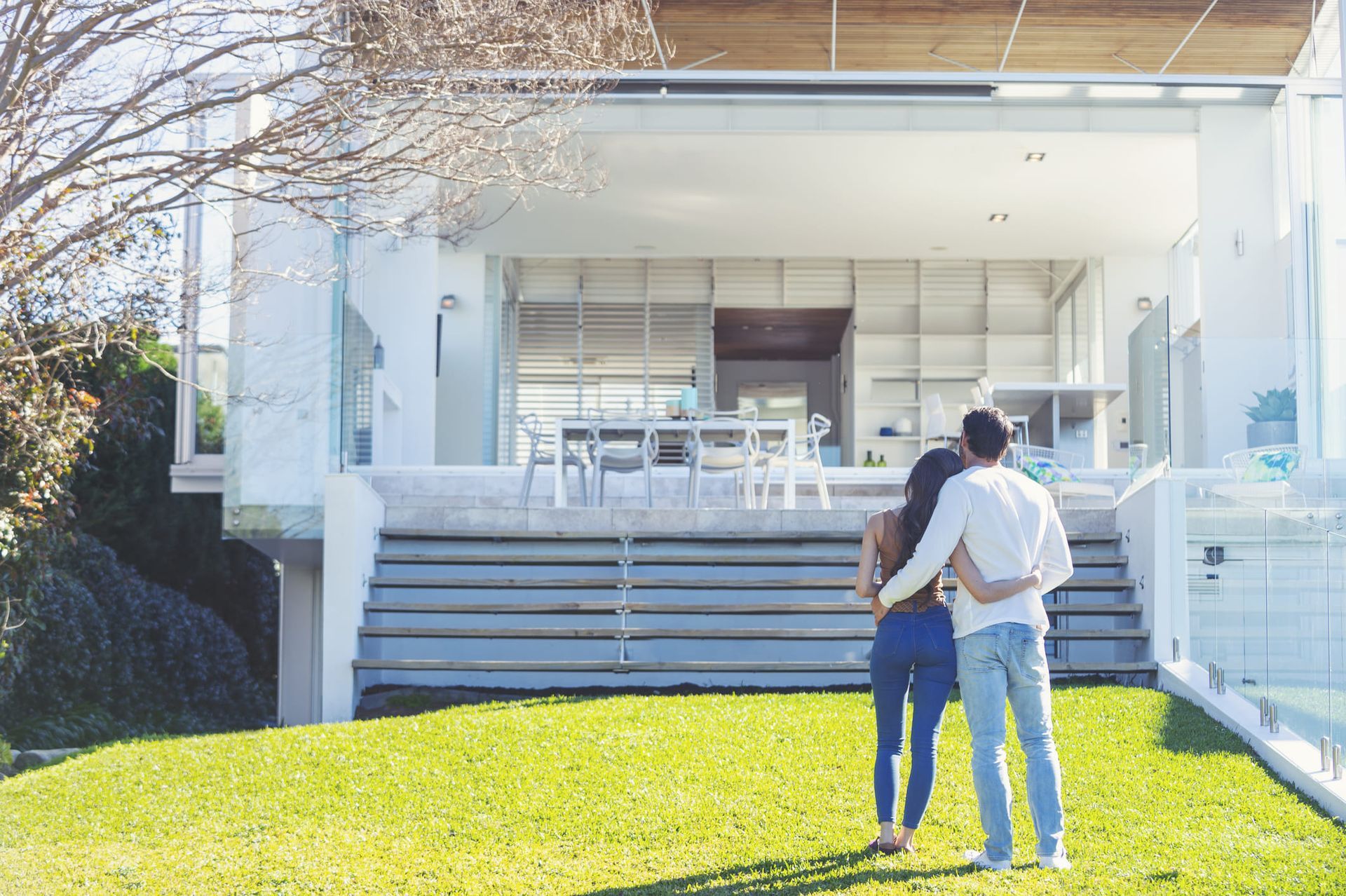 A man and a woman are standing in front of a house.