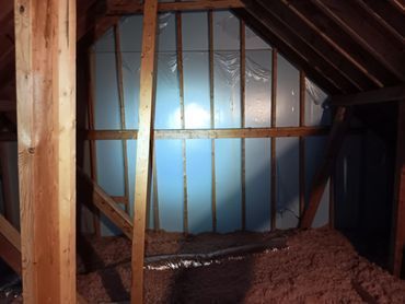 Attic interior with insulation and partially framed walls. Pink insulation on floor, blue foam board on wall.