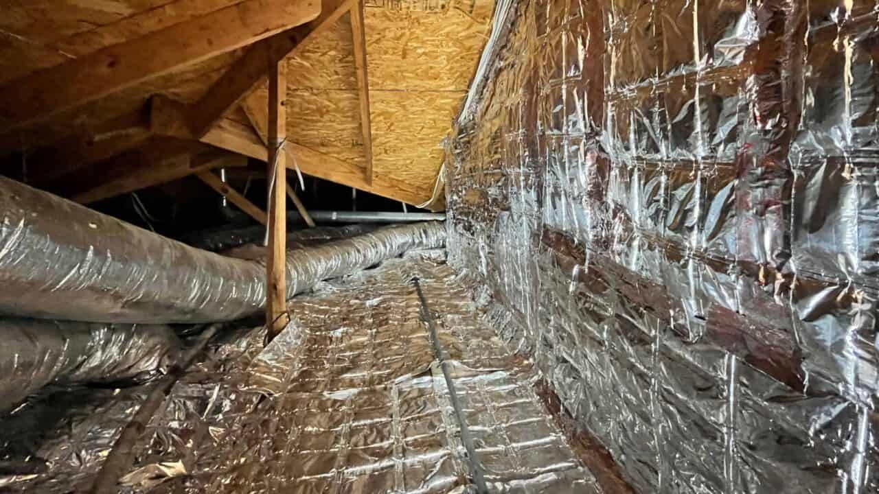 Attic with insulated ductwork and foil radiant barrier on the walls.