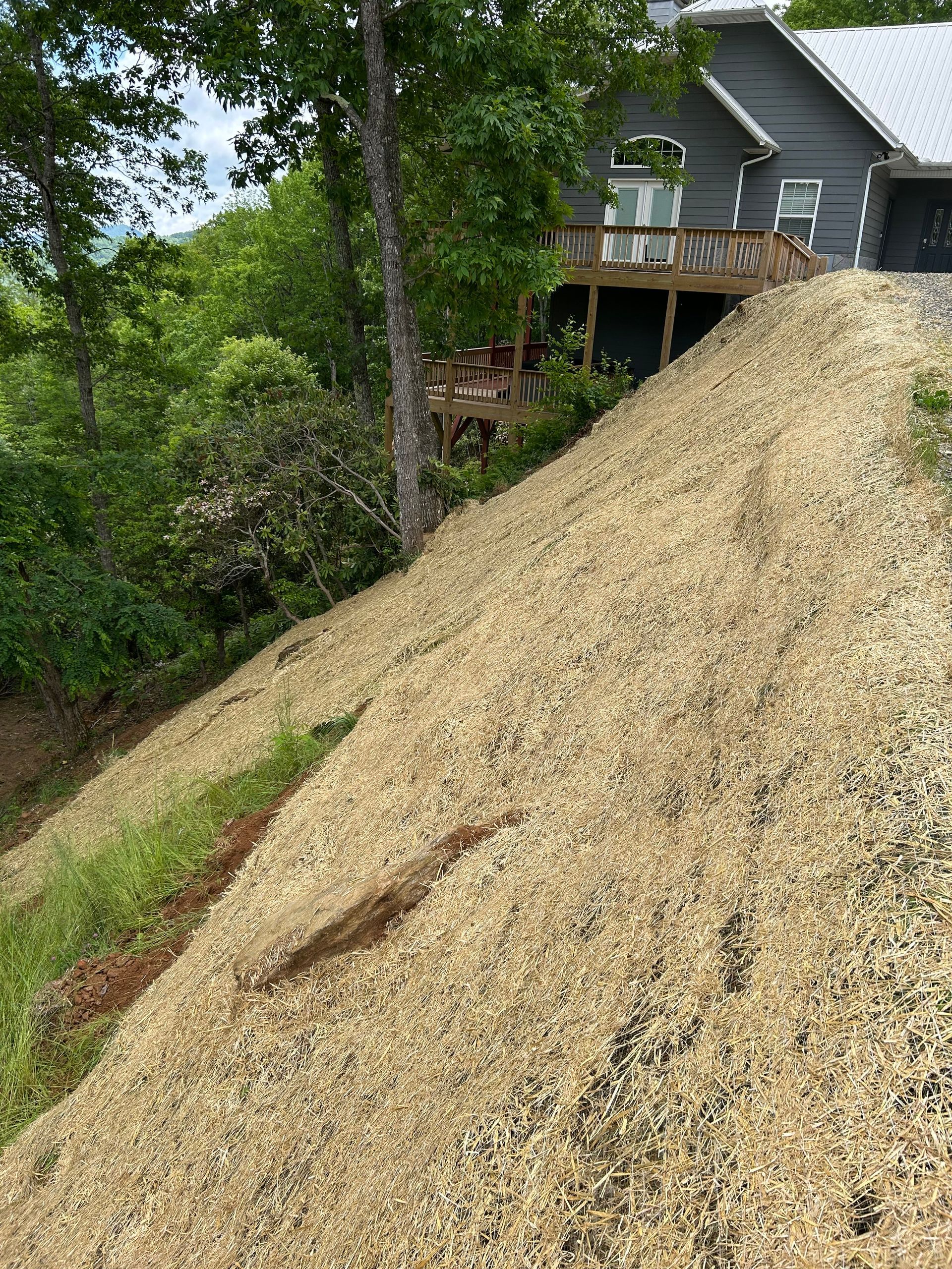 Large gravel mound beside a house deck, with trees and greenery in the background