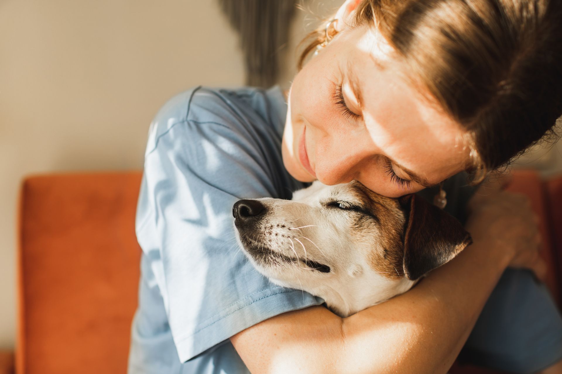 Cute young woman playing and hugging her jack russell terrier dog.