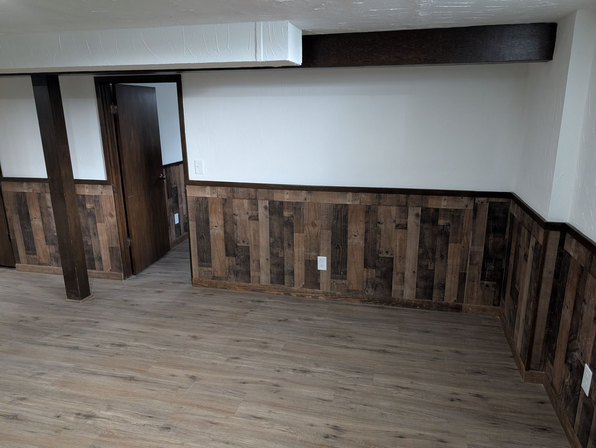 Empty rustic basement room with wood-paneled lower walls and a single doorway. Empty rustic basement room with wood-paneled lower walls and a single doorway.