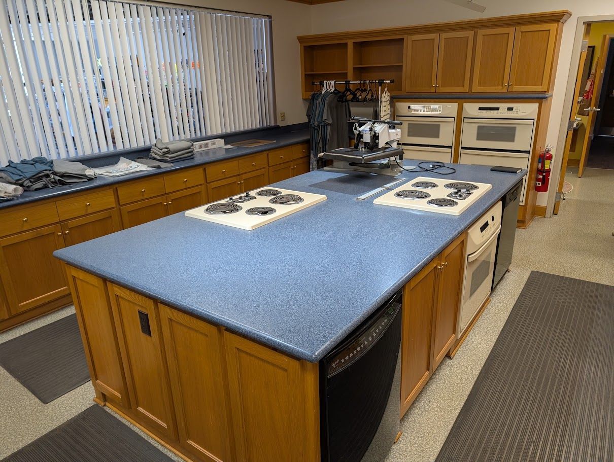 Kitchen with a large blue island, wood cabinets, stove, and patterned curtains by the window