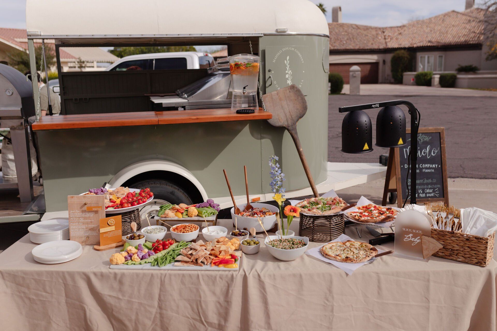 A table with a lot of food on it in front of Beyond Basil Mobile Pizzeria.