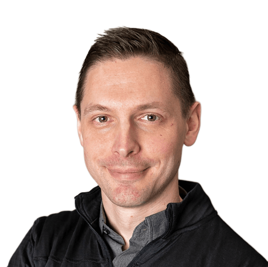 A man wearing a black jacket and a grey shirt is smiling for the camera.