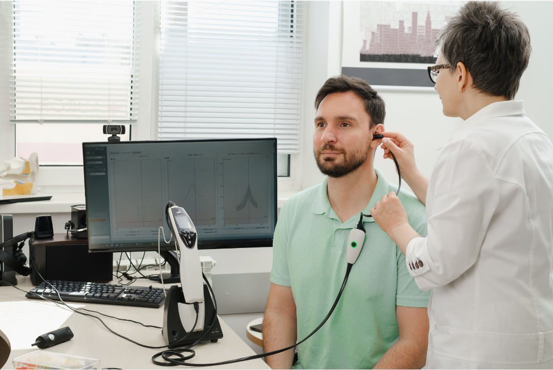 Audiologist performing a tinnitus assessment on a patient using diagnostic ear equipment in a clinic