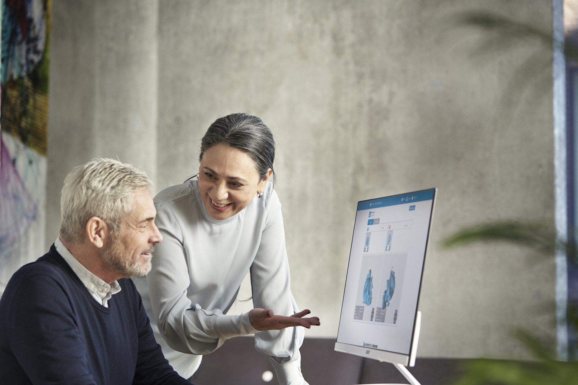 A man and a woman are looking at a computer screen.