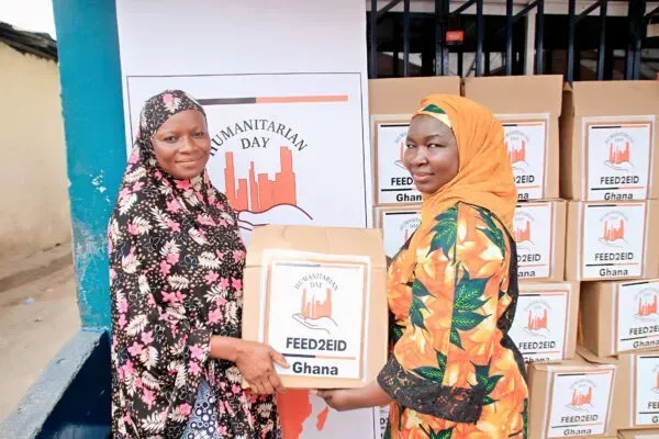 Two women in headscarves holding a box labeled 