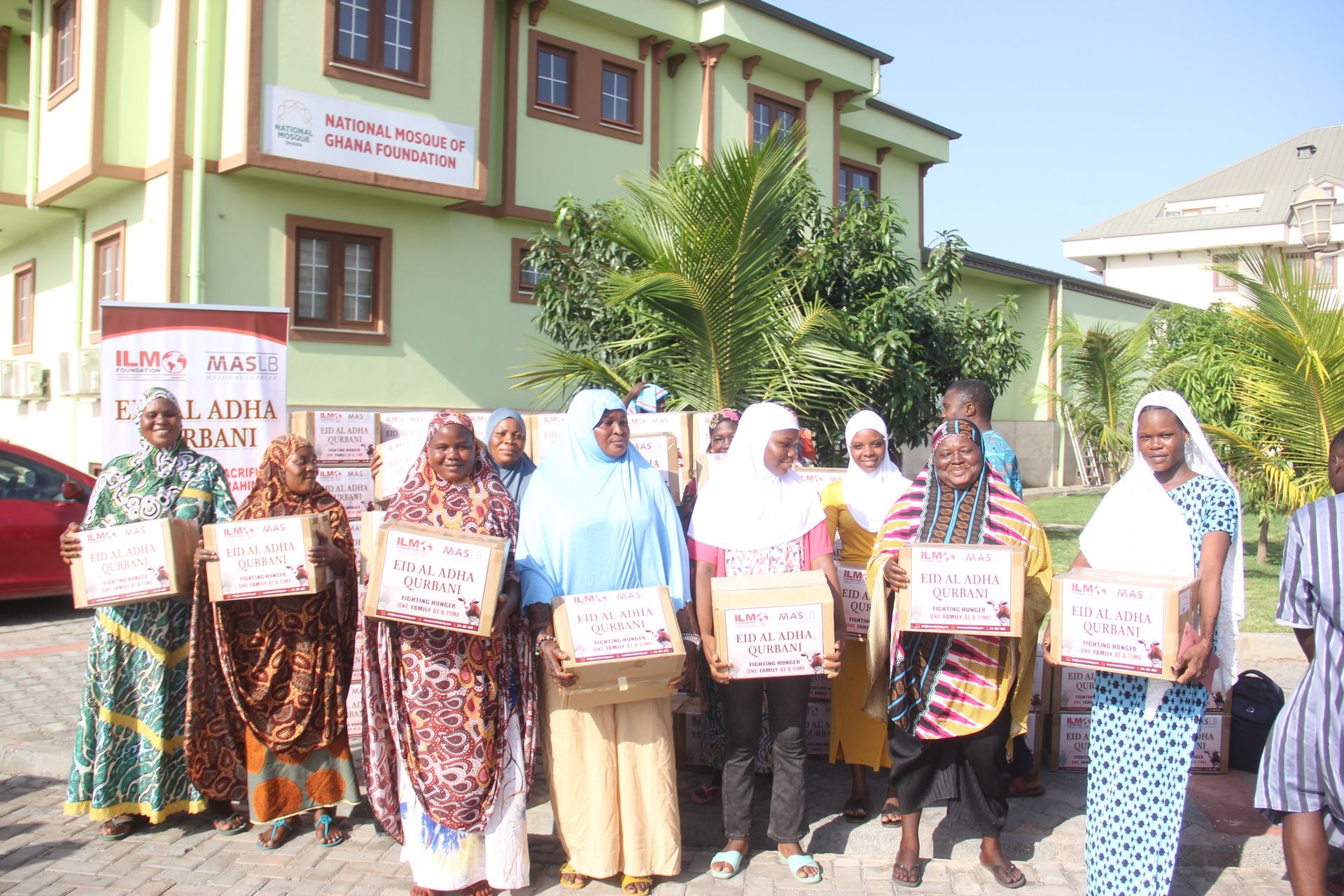 A group of women standing in front of a building holding boxes