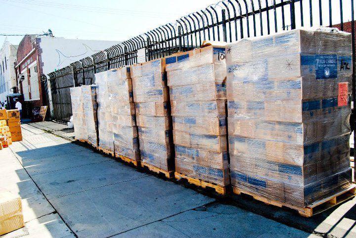 Pallets of packaged goods stacked outside a building, wrapped in plastic.
