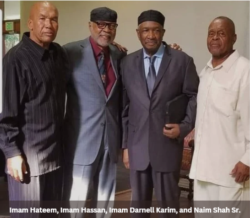 Four Black men in suits pose together.