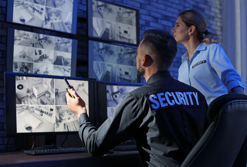A Man and a Woman Are Looking at Monitors in a Security Room — Cambush Security Solutions NT in Alice Springs, NT