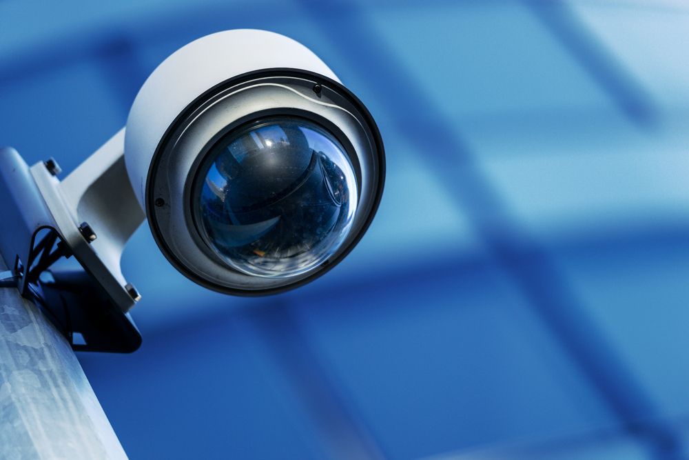 A Security Camera is Mounted to a Pole on a Blue Wall — Cambush Security Solutions NT in Katherine, NT