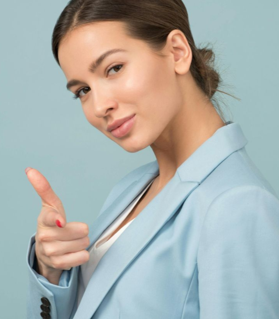 Woman in blue blazer points with a confident expression; light blue backdrop.