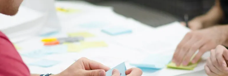 People at a table, working with sticky notes and papers.