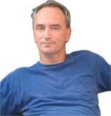 Man in blue shirt, looking directly at the camera, neutral expression.