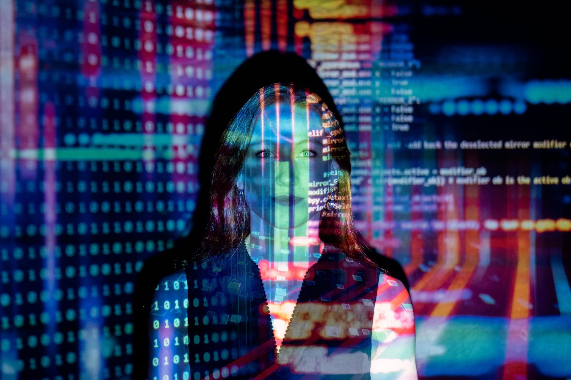 Woman in a hoodie, overlaid with colorful digital code and data streams.