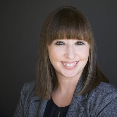 A woman in a gray jacket is smiling for the camera.