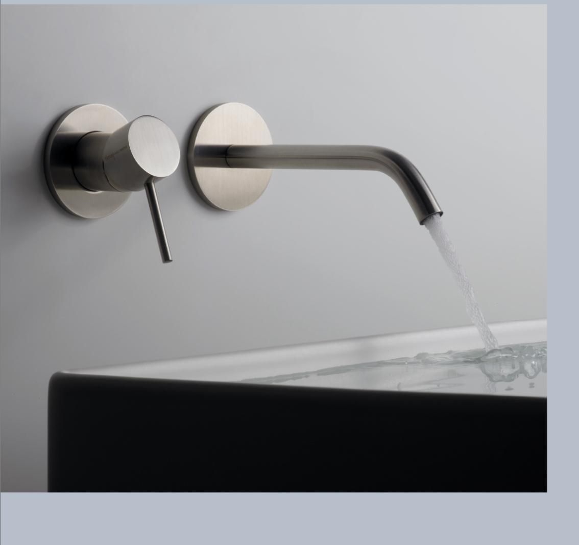 Rubinetto moderno a parete con acqua che scorre in una vasca da bagno, contro una parete grigia.