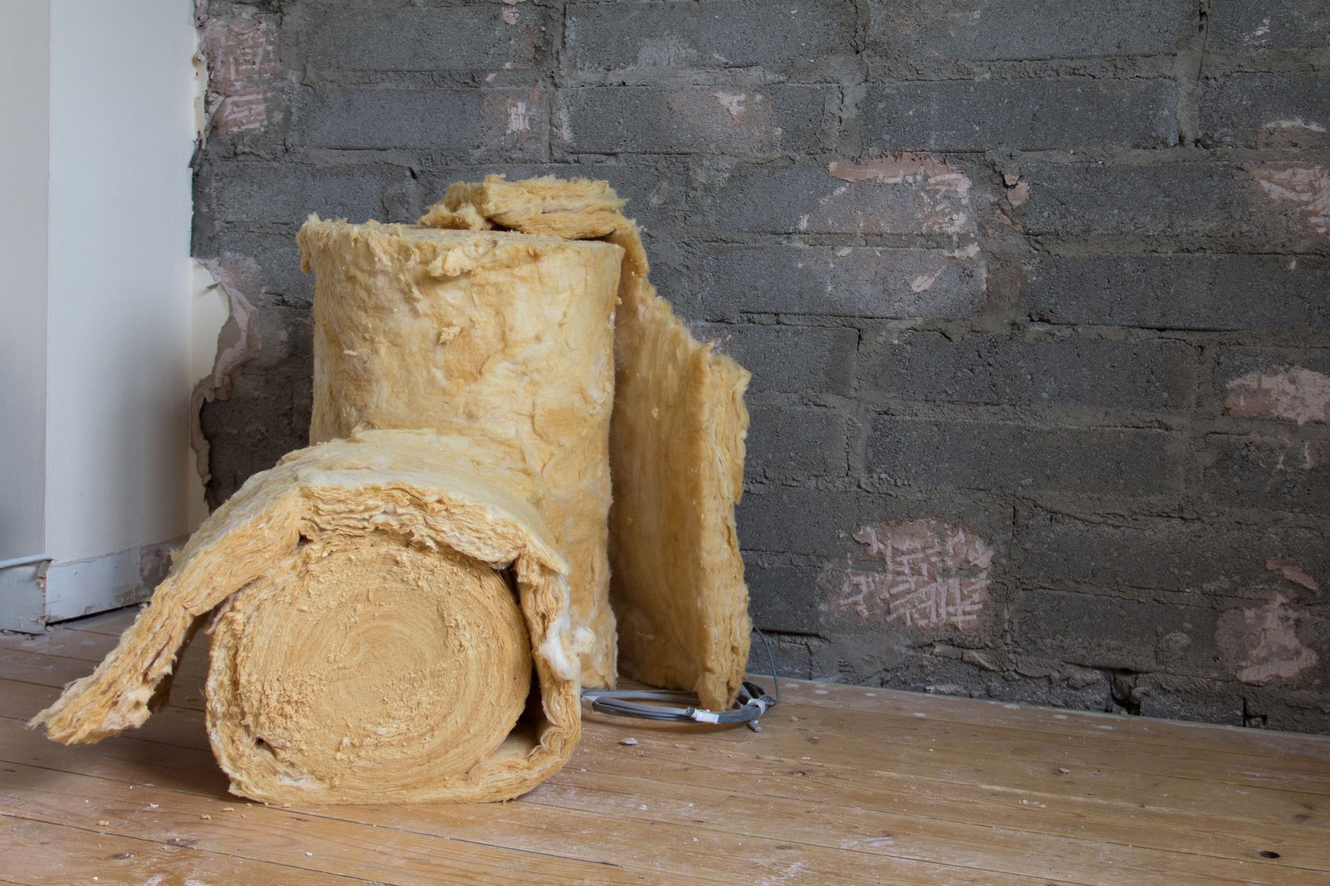 Two rolls of insulation material on the floor of a room
