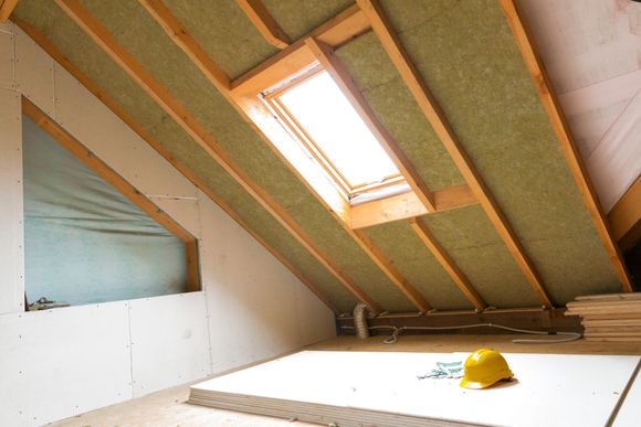 Insulation Service — Ham Lake, MN — Gunner General Contracting Interior view of an attic under construction with insulation between rafters, a skylight, and drywall.
