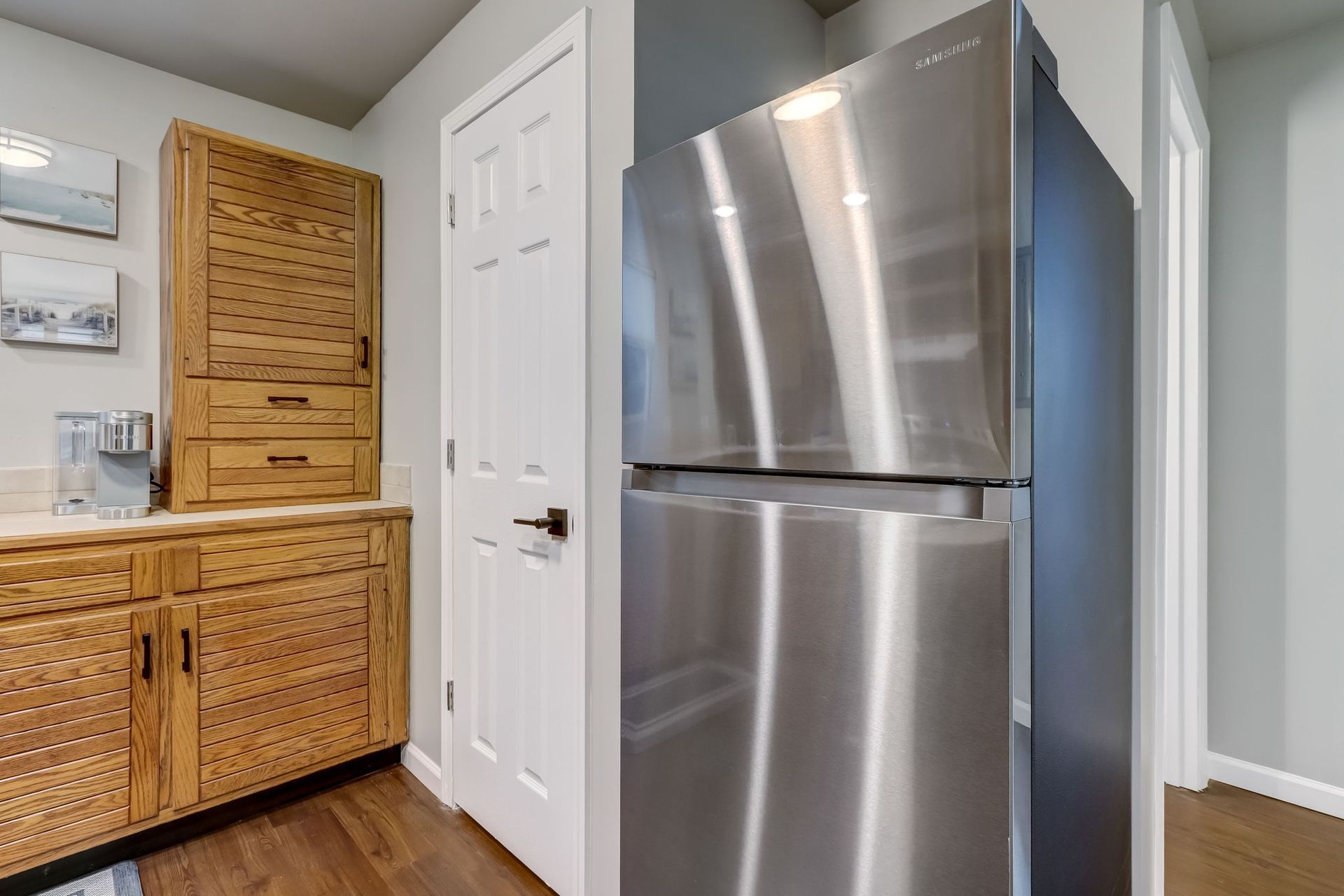 A kitchen with a stainless steel refrigerator and wooden cabinets.