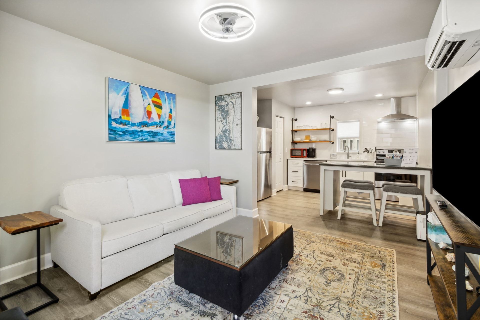 A living room with a white sleeper sofa , coffee table , and smart flat television.