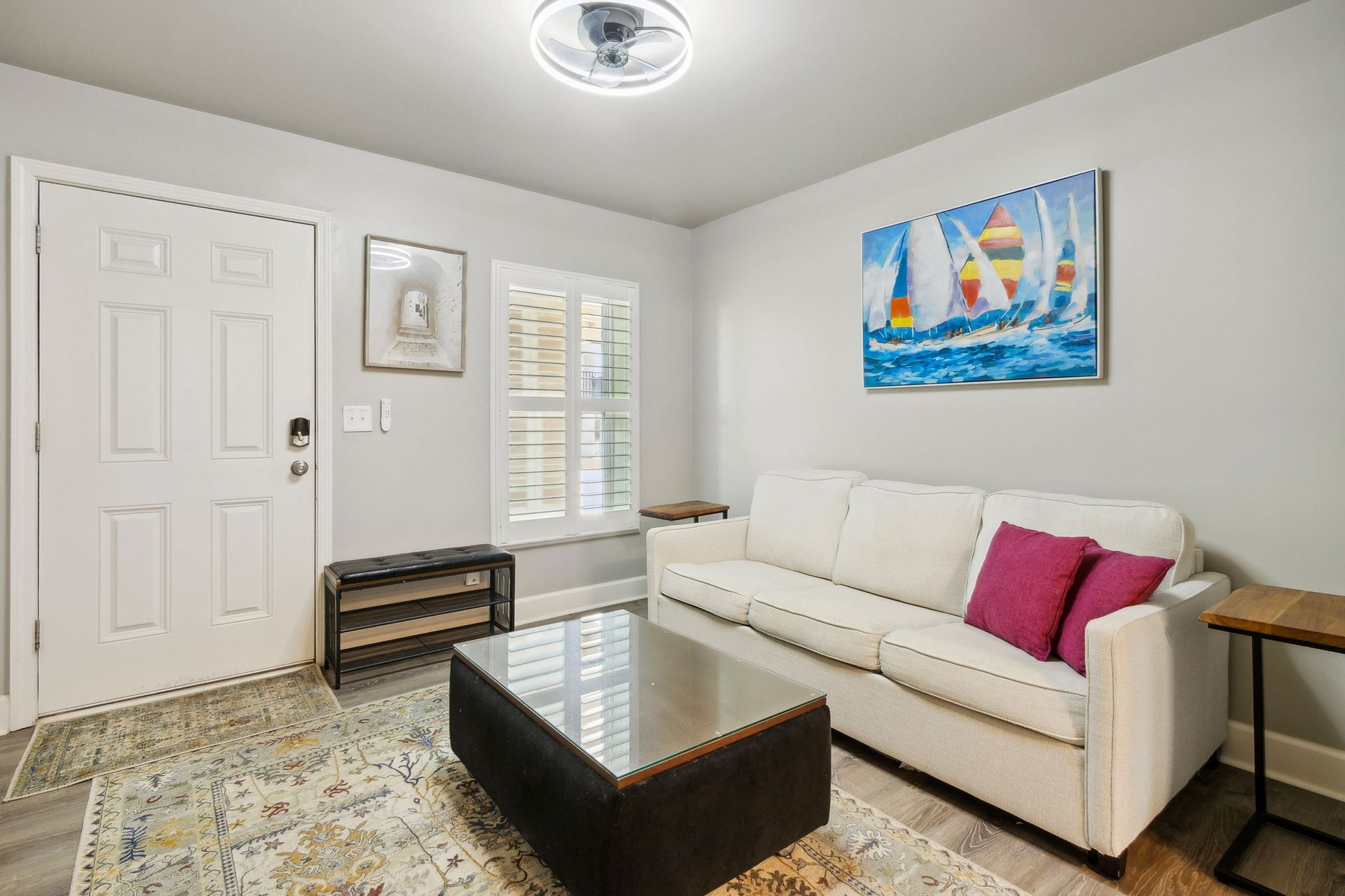 A living room with a couch , coffee table , and a painting on the wall.