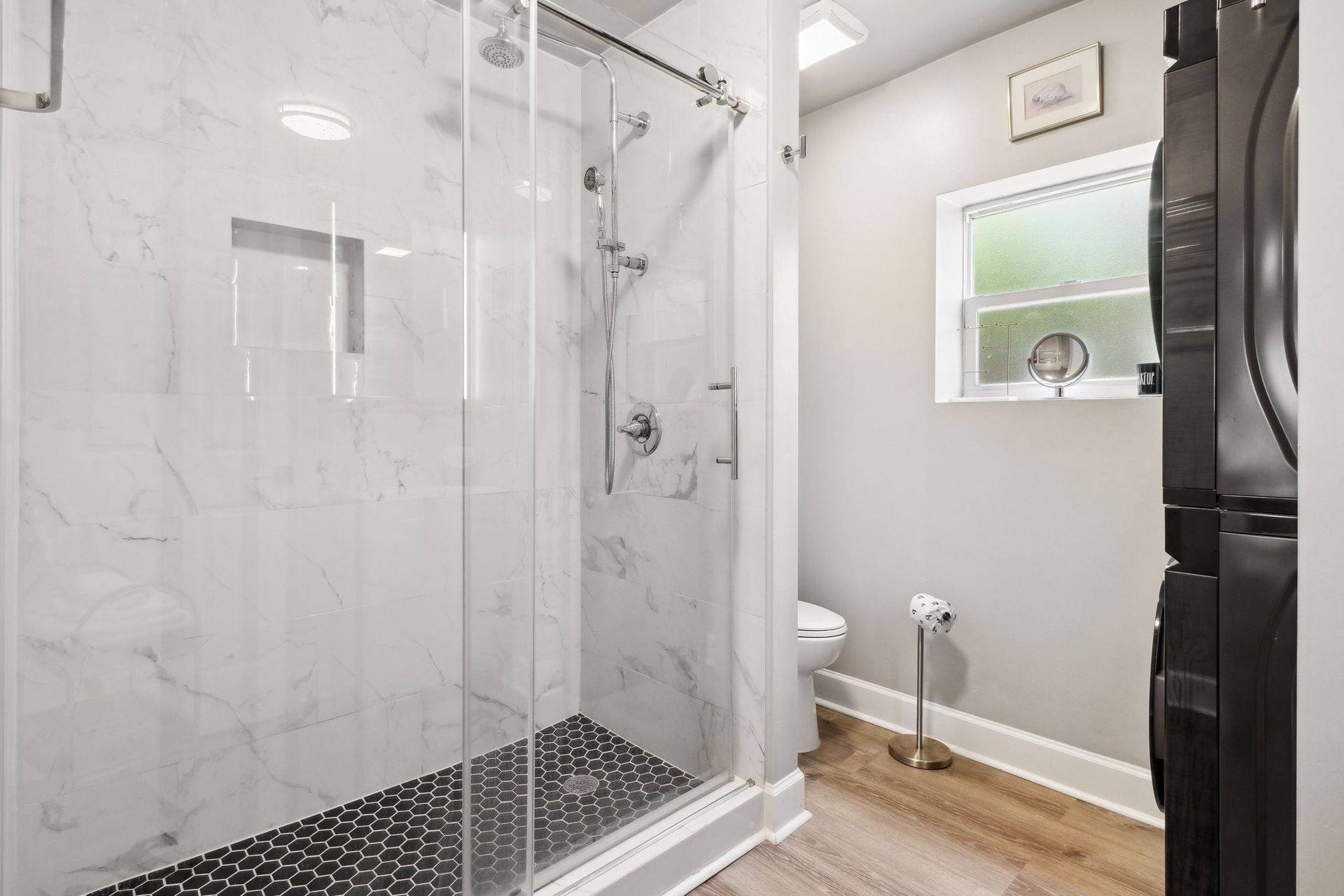 bathroom with an oversized custom tile shower and stackable large washer/dryer 