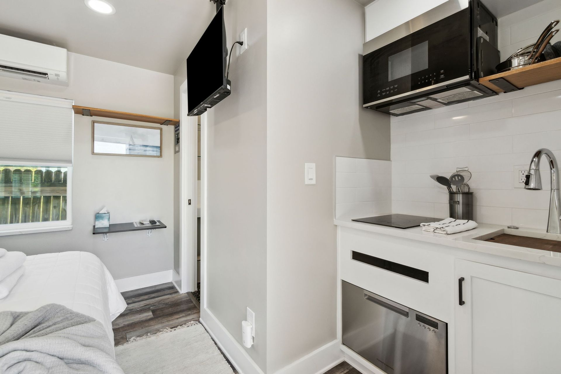 A small kitchen with a sink , stove , microwave and television.