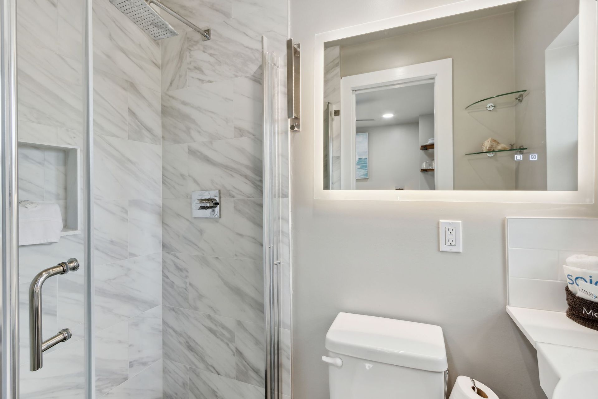 A bathroom with a toilet , shower and mirror.