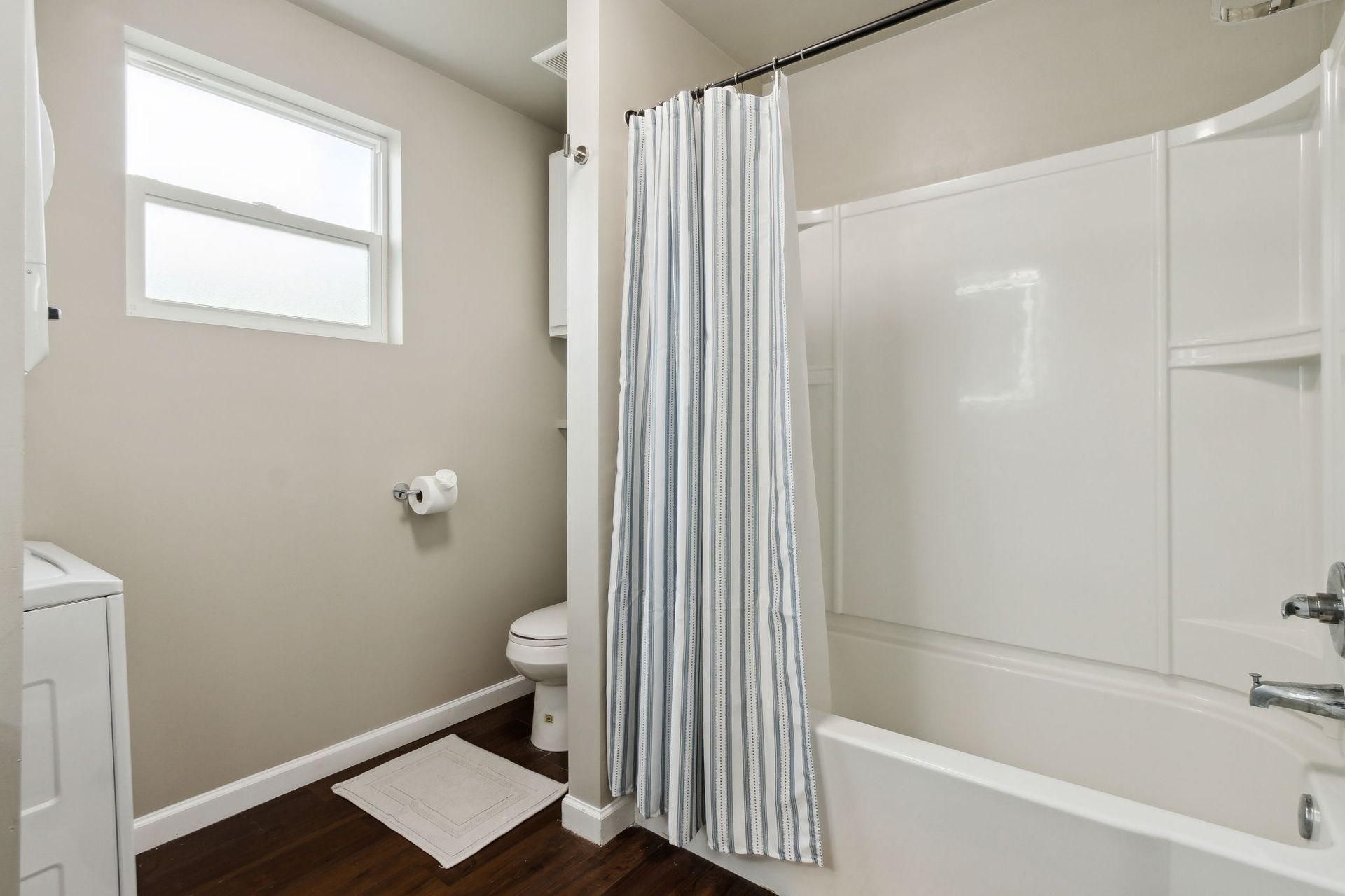Full bathtub and a toilet with overhead shelving