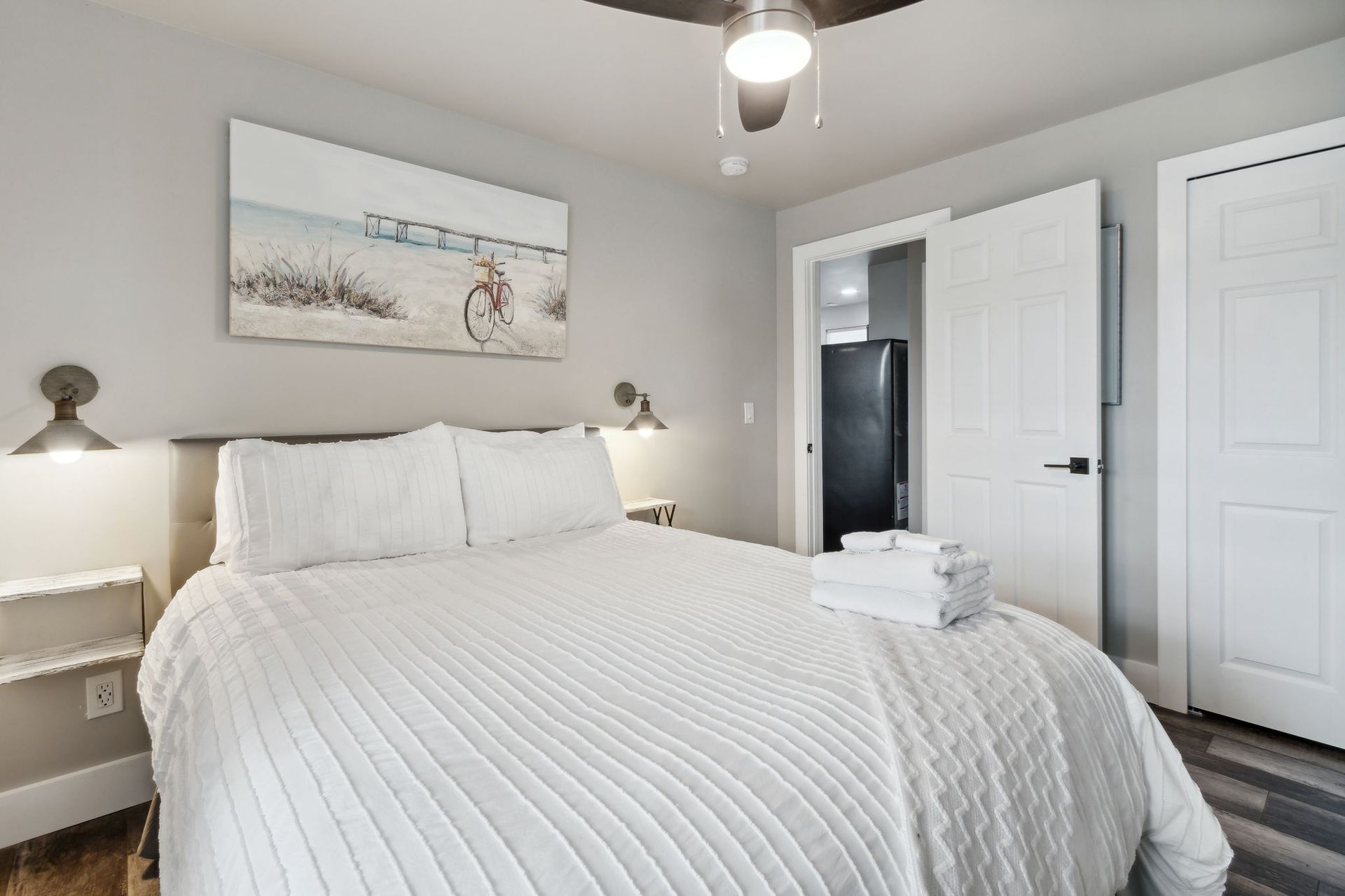 A bedroom with a queen size bed, mini split air conditioning unit and a ceiling fan.
