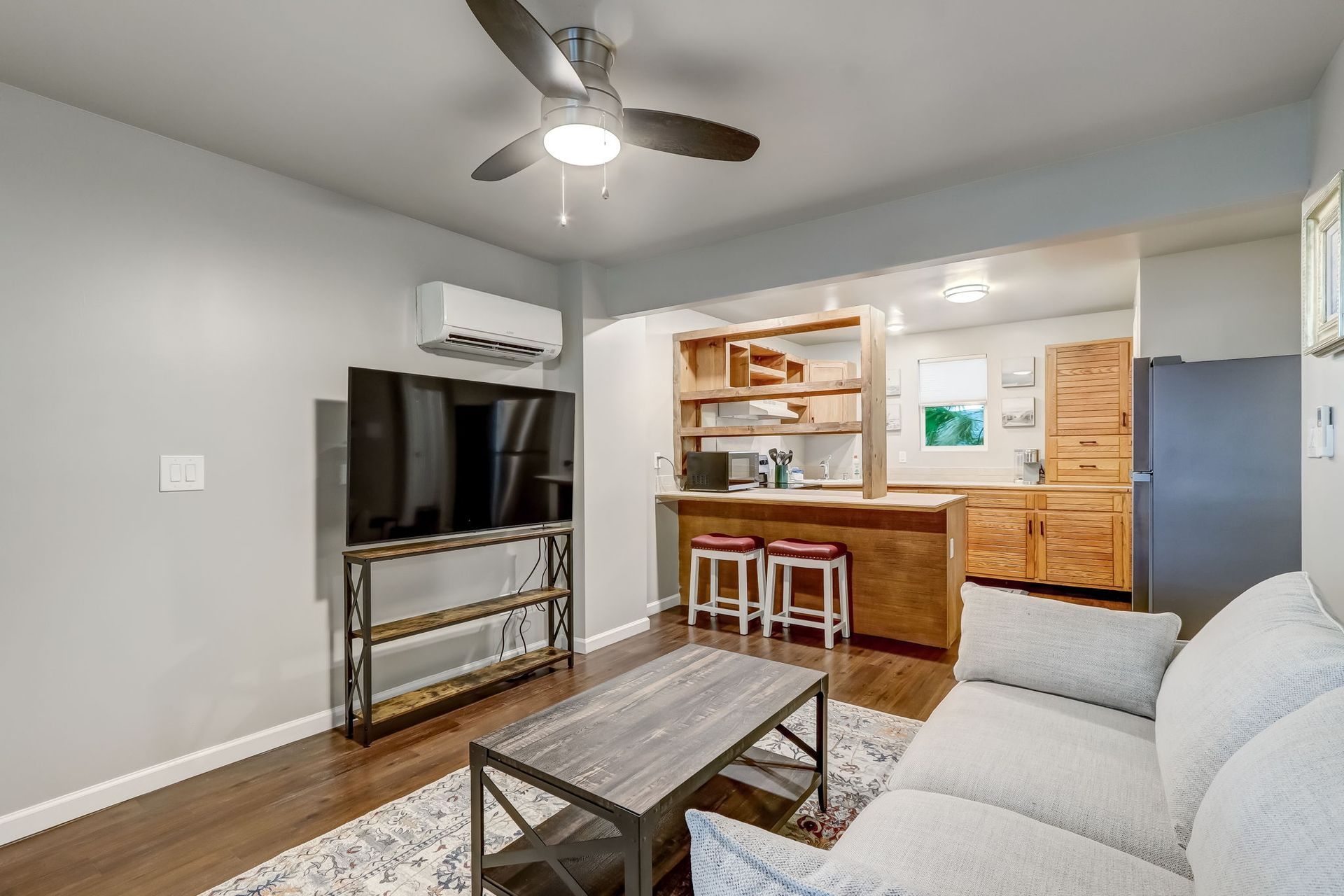 Living room with a couch, flat screen smart TV, couch, coffee table and a ceiling fan. 