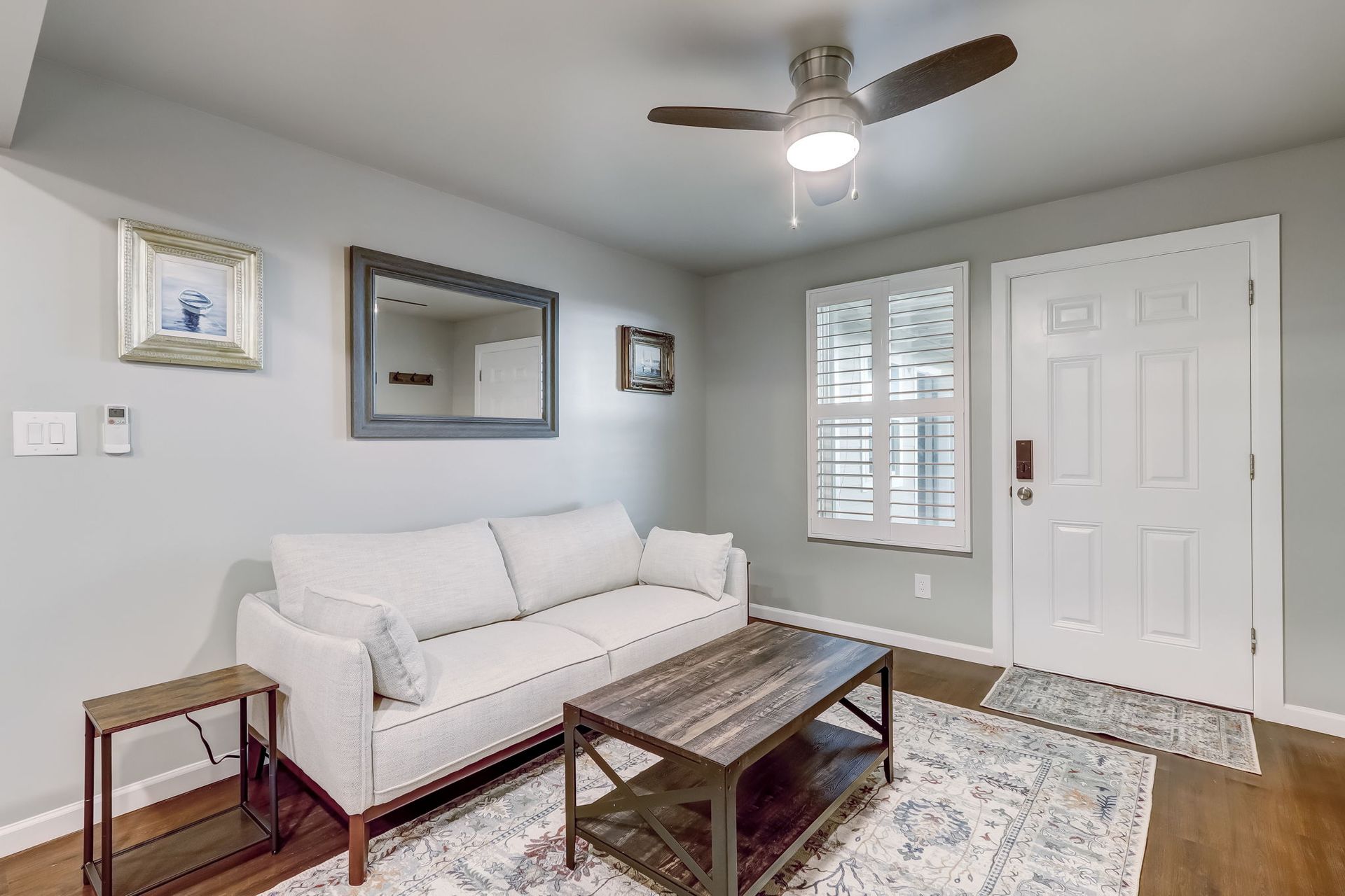 Living room with a couch, flat screen smart TV, couch, coffee table and a ceiling fan. 