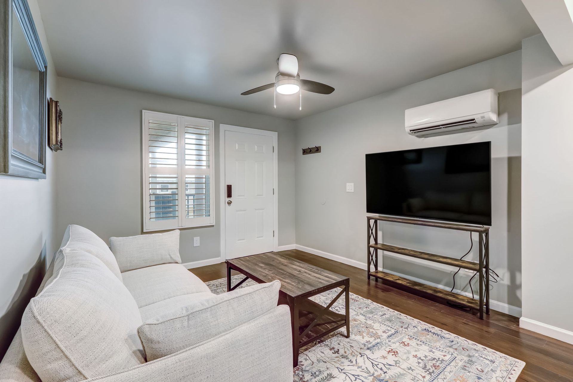 Living room with a couch, flat screen smart TV, couch, coffee table and a ceiling fan. 