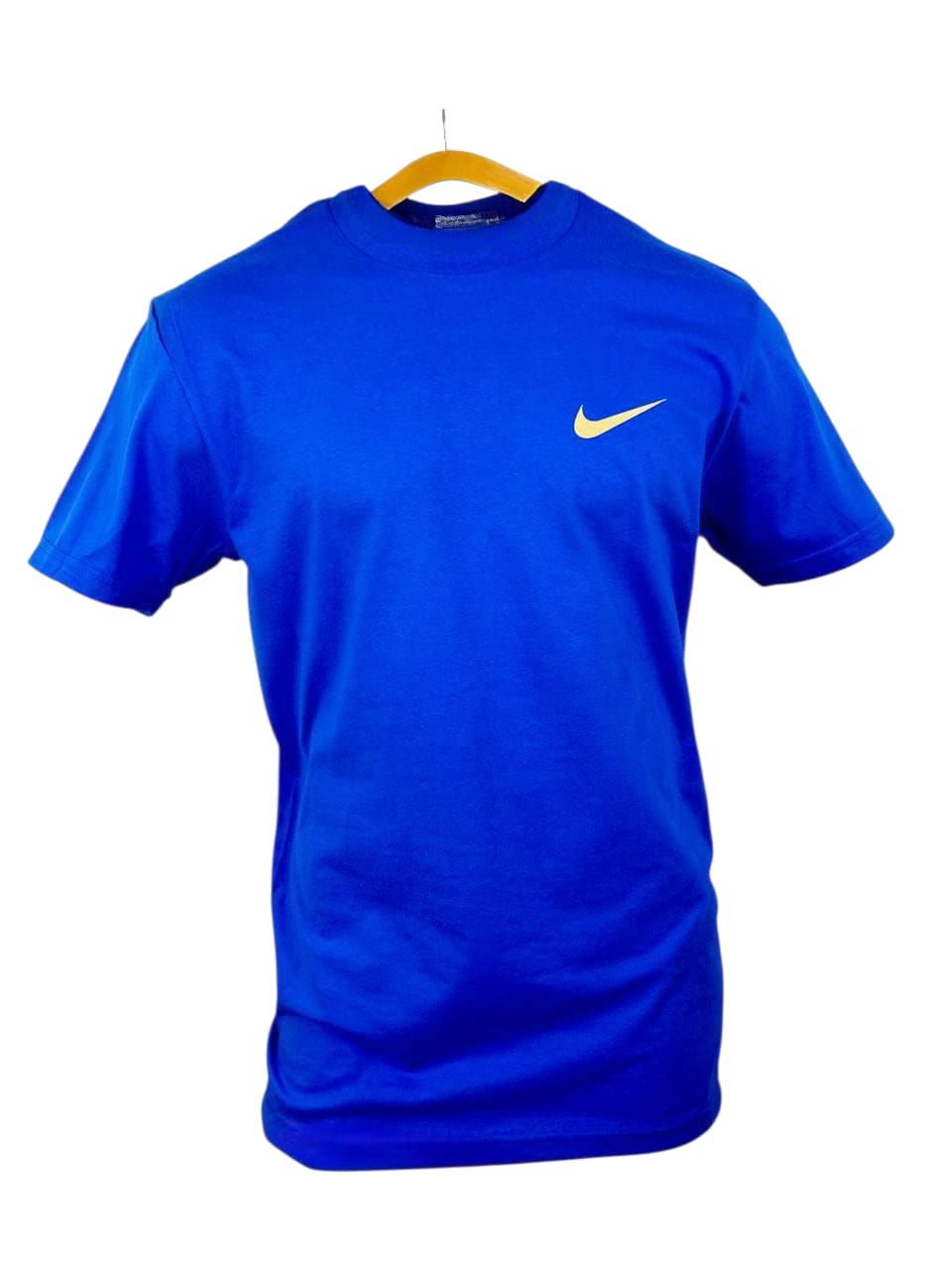 Camiseta azul de fútbol Nike con gráfico blanco, mostrada con dos balones de fútbol en un campo bajo las luces del estadio.