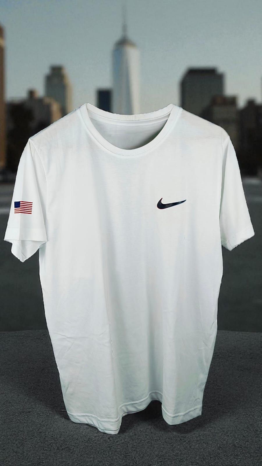 Camiseta blanca de Nike en un maniquí con un fondo que muestra el perfil de una ciudad.