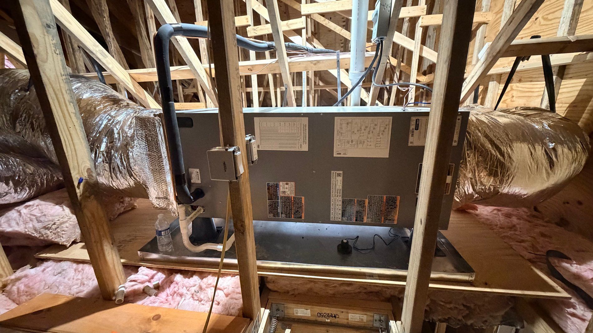 Attic with exposed rafters, HVAC ductwork, and a central furnace/air handler under construction.